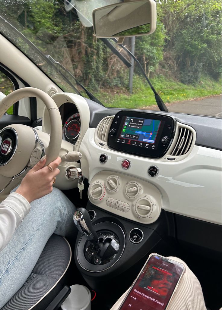 the interior of a small car with an electronic device in the center and steering wheel