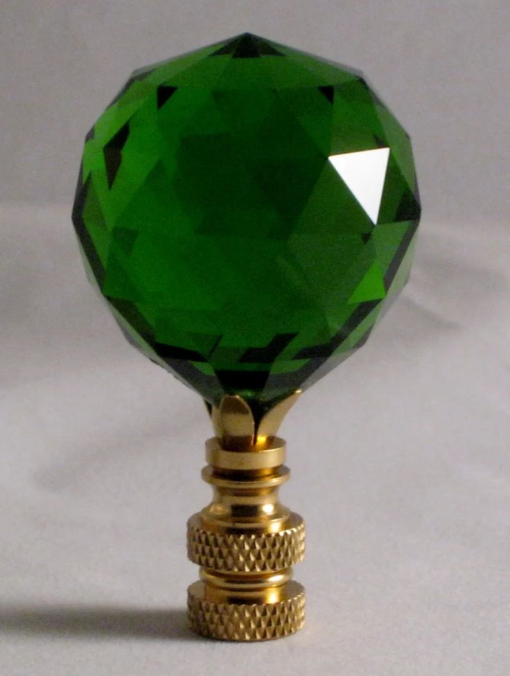 a green crystal ball on top of a golden stand