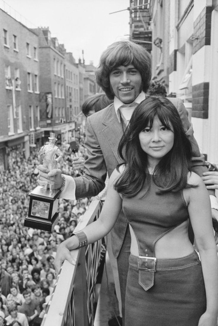 an old photo of two people in front of a crowd holding trophies and posing for the camera