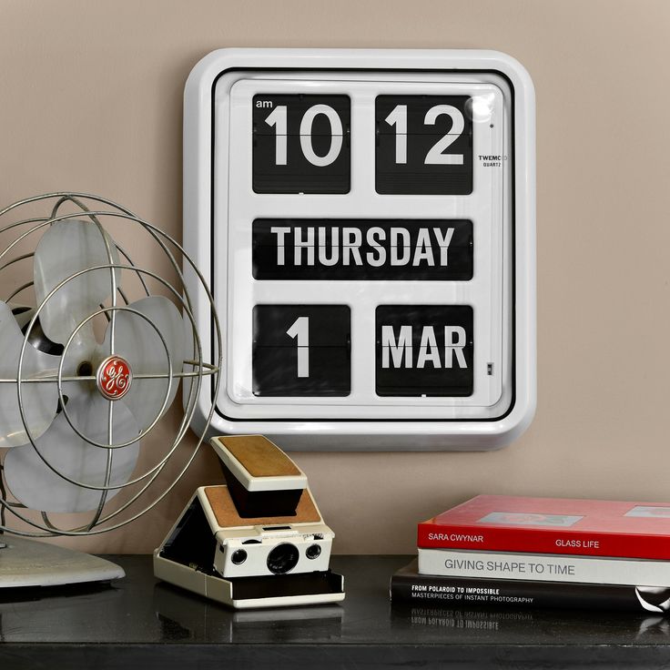 an alarm clock sitting on top of a desk next to a fan