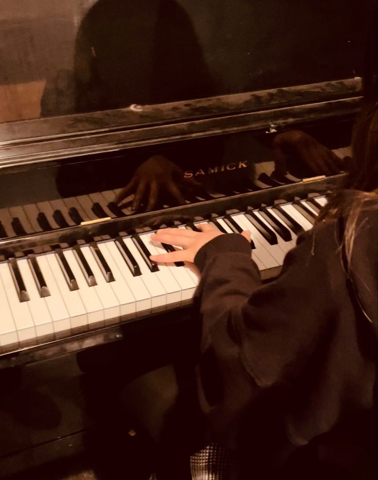 a person sitting at a piano with their hands on the keys