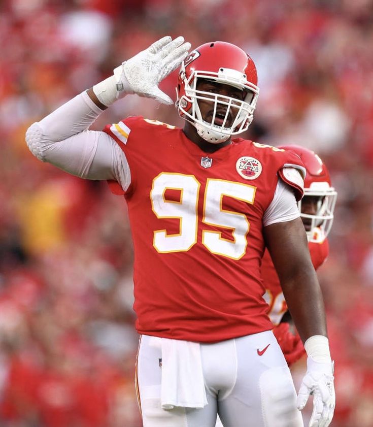 a close up of a football player holding his hand in the air while wearing a helmet