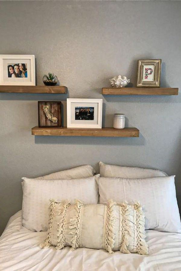 a bed with white linens and two wooden shelves above it