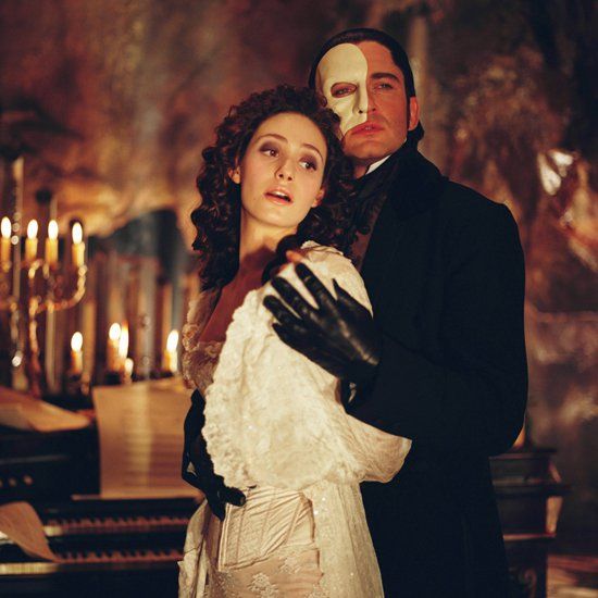 a man and woman standing next to each other in front of a piano with candles