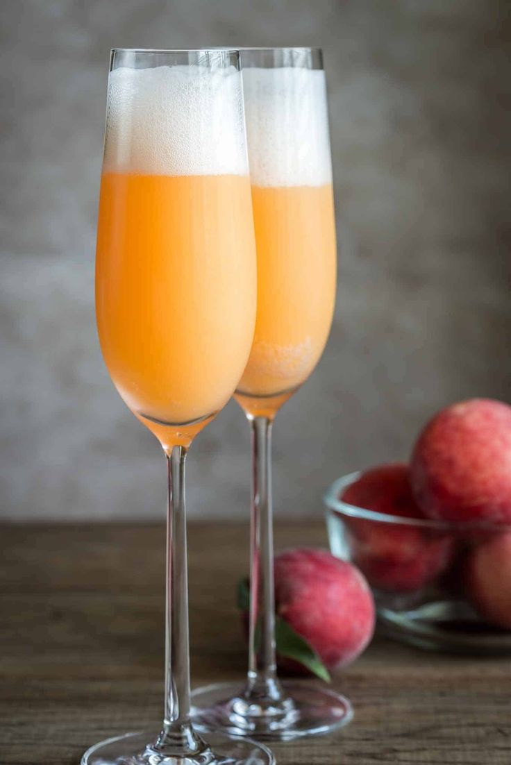 two wine glasses filled with champagne sitting next to apples