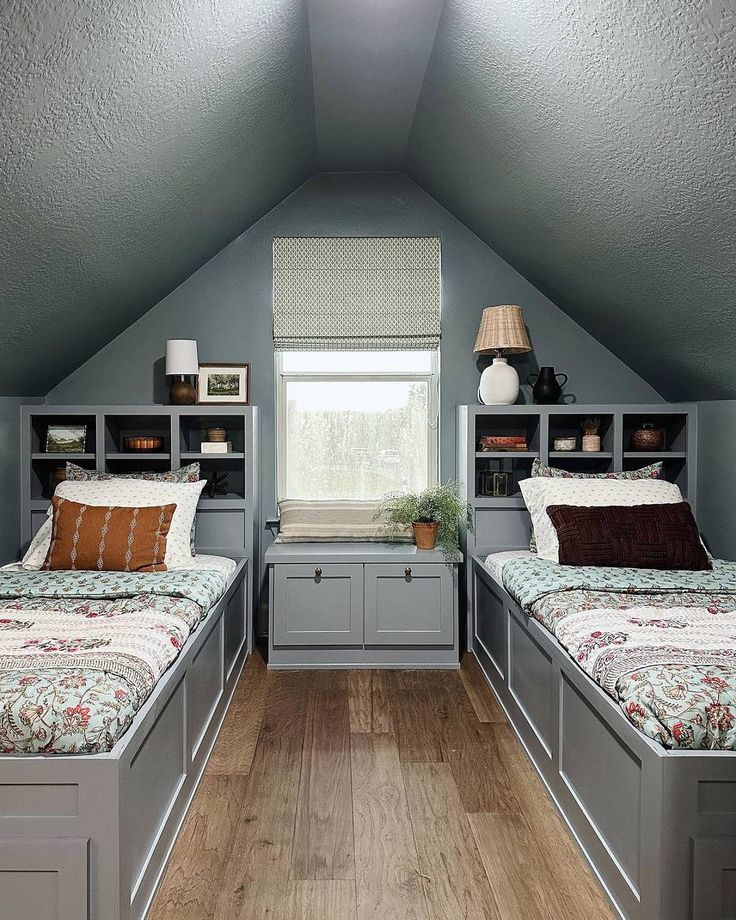 two beds in a room with built - in bookcases on the wall and wooden floors