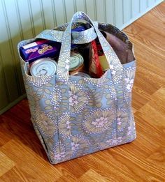 a bag that is sitting on the floor with some food in it and soda cans