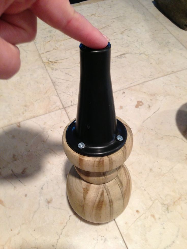 a person is touching the top of a wooden device holder with their thumb on it