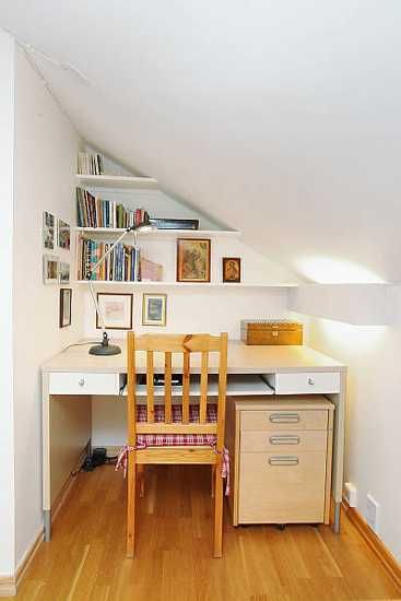 a desk and chair in a small room with wooden floors, bookshelves and pictures on the wall