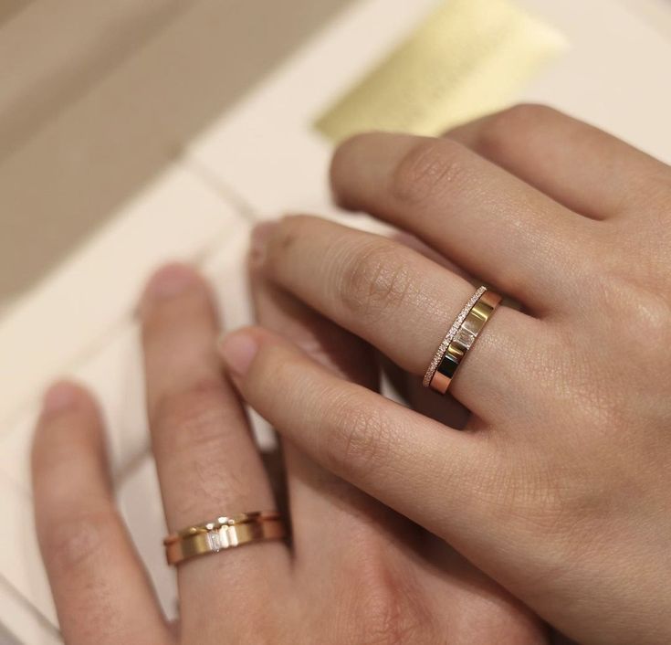 two hands holding each other with gold rings