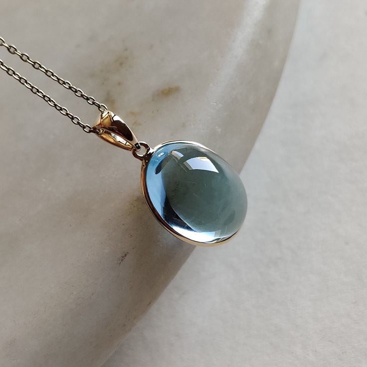 ITEM DESCRIPTION: >>The pendant is made from Solid 14K Yellow Gold. Gemstone used is absolutely natural and ethically sourced. >>Natural Sky Blue Topaz in cabachon and oval shape with bezel setting is studded on it with utmost precision. >>This is a minimalist design and is absolutely hassle-free and everyday jewelry. Gem: Sky Blue Toapz Gem size: 12x16 mm oval Gem weight: 13.6 carats Gold purity: 14K (58.33% approx.) Gold weight: 0.56 grams Gross weight: 3.22 grams The Gold purity is guaranteed Gemstone Pendant For Men, Round Light Blue Topaz Necklace, Light Blue Round Blue Topaz Necklace, Blue Topaz Briolette Jewelry Gift, Fine Jewelry Light Blue Gemstone, Blue Topaz Gemstone Drop Jewelry, Blue Topaz Briolette Jewelry For Gifts, Blue Aquamarine Drop Jewelry, Light Blue Jewelry With Gemstone Accents For A Gift