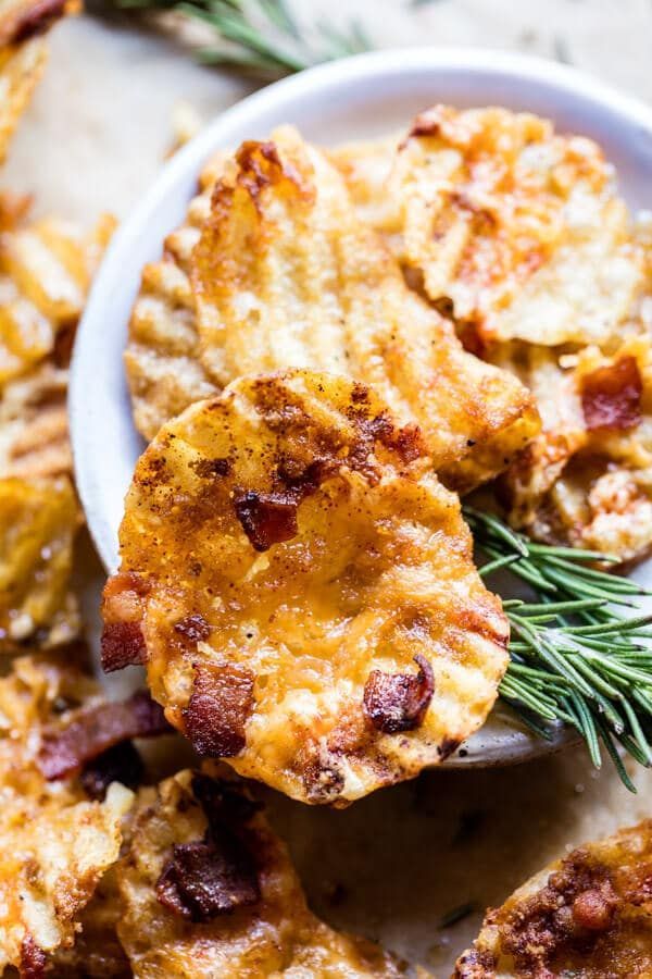 some crackers are in a white bowl on a table with rosemary sprigs