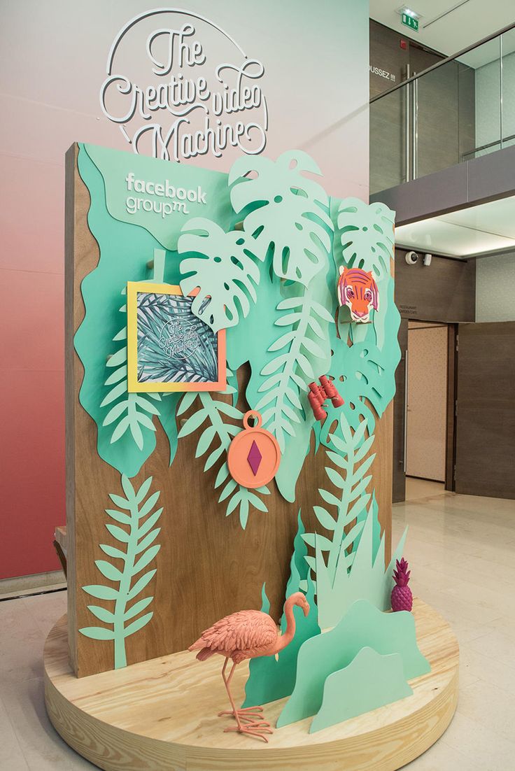 a cardboard sculpture of a flamingo in front of a palm tree