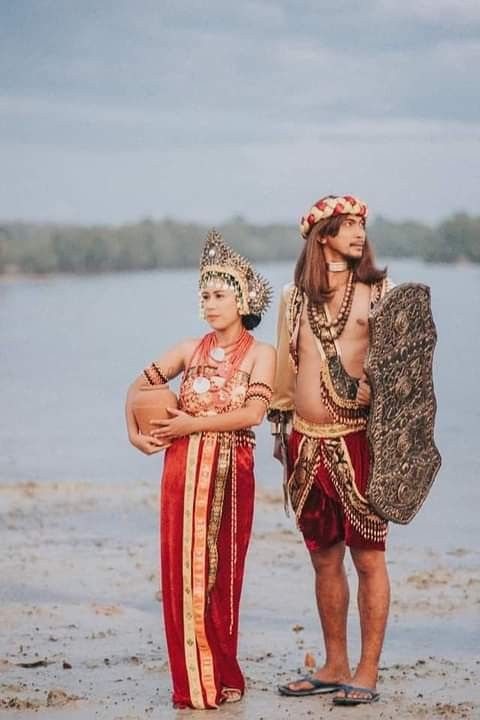 two men dressed in costumes standing on the beach with their arms around each other's shoulders