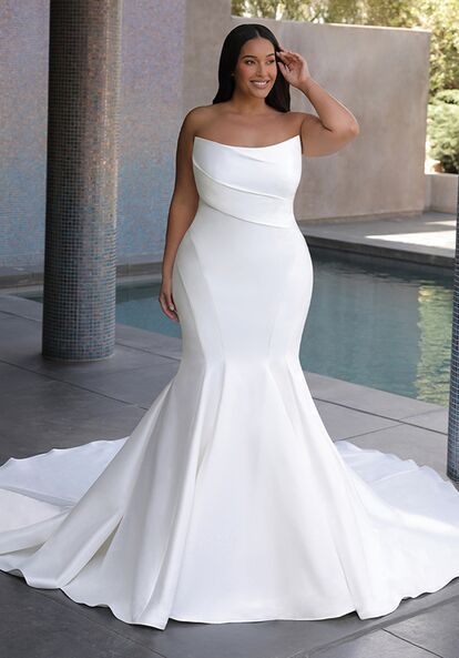 a woman in a white wedding dress standing next to a pool