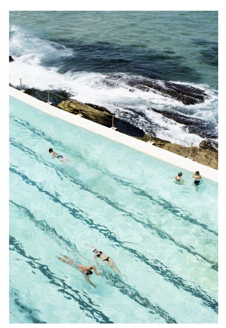 people are swimming in an outdoor pool near the ocean