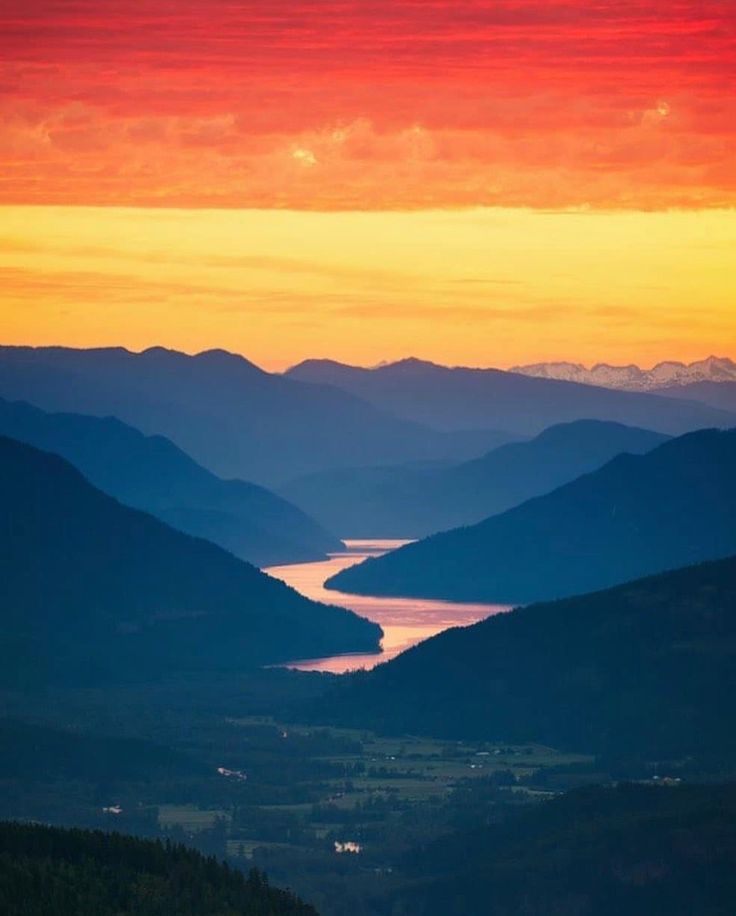 the sun is setting over some mountains and water