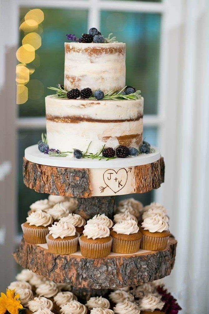 a three tiered wedding cake with cupcakes on the bottom and berries on top