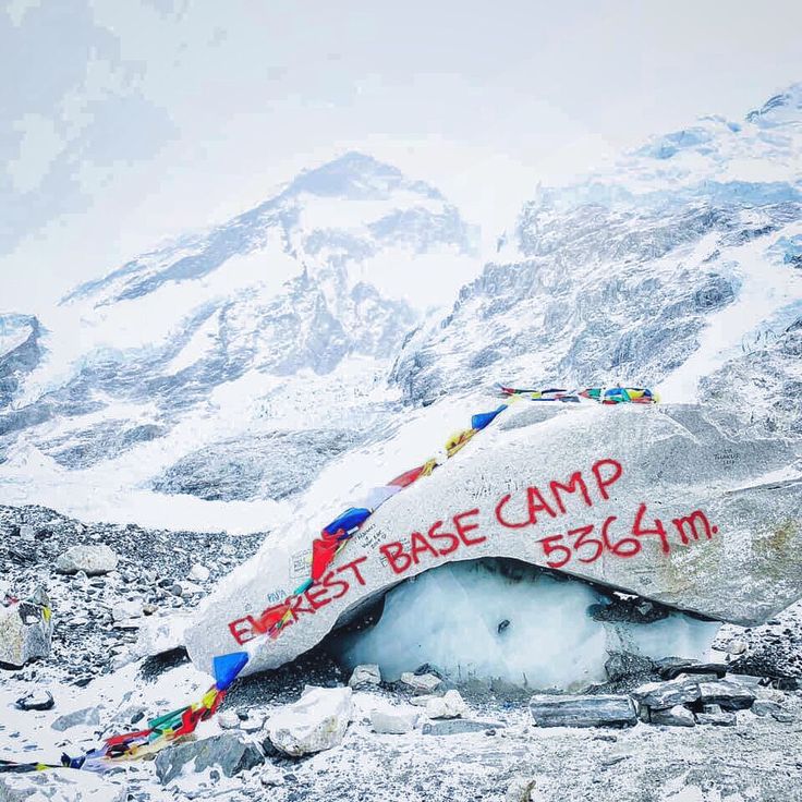 a sign that is on the side of a mountain with snow and flags around it