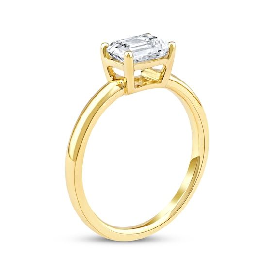 a yellow gold engagement ring with an emerald cut diamond in the center, on a white background