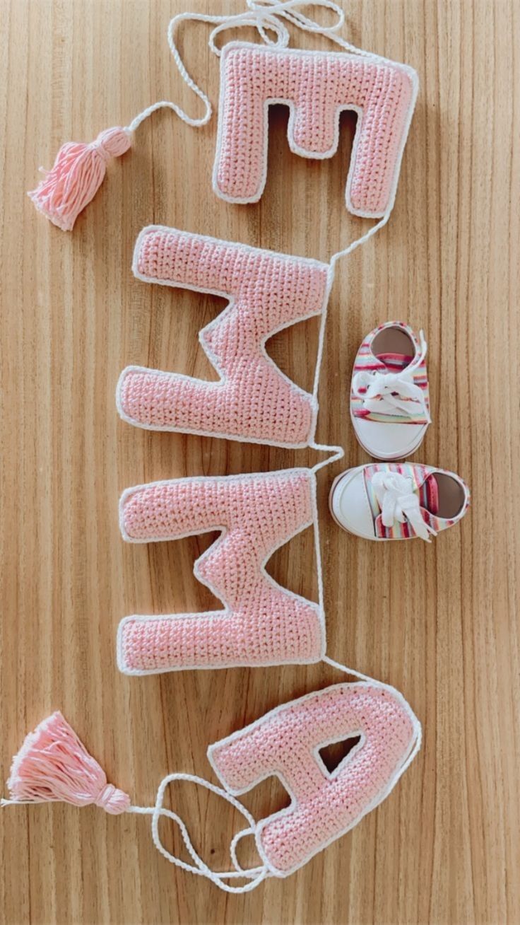 knitted letters spelling out the word happy on a wooden surface with shoes and yarn