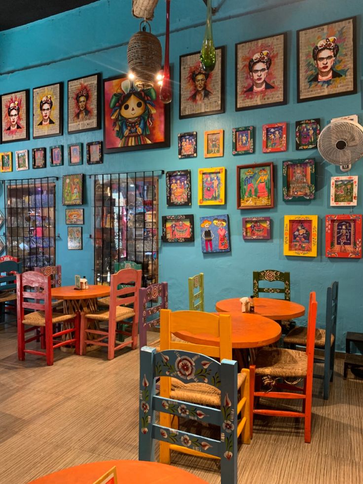 colorful tables and chairs in a restaurant with pictures on the wall