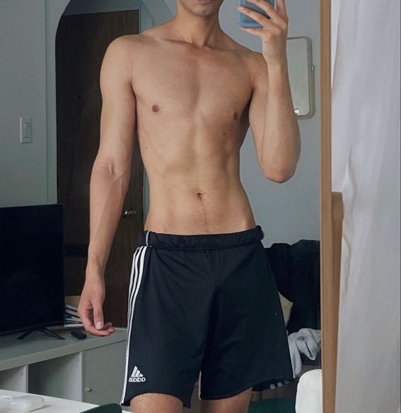 a shirtless man taking a selfie in the mirror