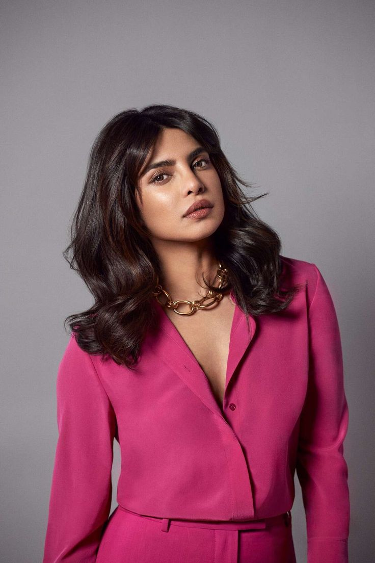 a woman in a pink suit posing for the camera with her hands on her hips