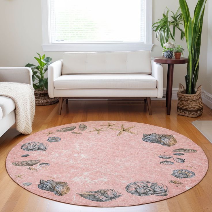 a living room filled with furniture and a pink rug on top of a hard wood floor