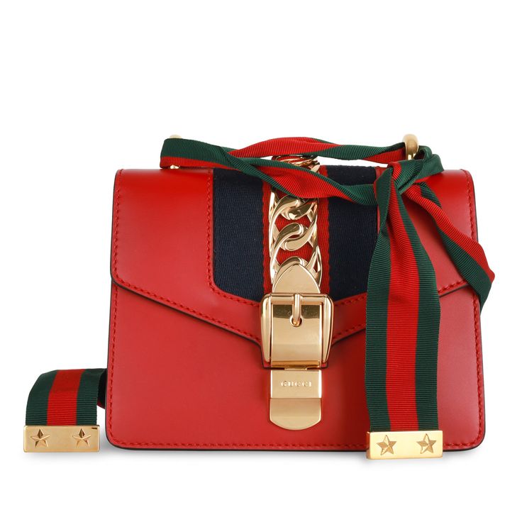 The Gucci Sylvie is one of those bags that became a classic the moment it landed in stores. Featuring the brand’s signature green and red front fabric stripe and a charming gold tone hardware chain strap, this mini Gucci is an absolute must-have, and iconic piece to own from the brand. SPL Exterior Smooth Red leather Gold toned hardware Chain buckle detail on front flap Red and navy fabric strip Gold tone chain crossbody strap Removable ribbon Excellent condition - minimal signs of wear except some hairline scratches to the hardware and closure. One small scratch to front left. Interior Beige microfibre suede like interior Single compartment Slip pocket Gucci embossed leather logo tag Excellent condition - small press mark under flap, inside is clean. Sold on its own SPL Height: 14cm Width Gucci Sylvie, Gucci Mini, Navy Fabric, Dior Shoes, Green And Red, Timeless Handbag, Chain Bag, Exclusive Bag, Chain Bags