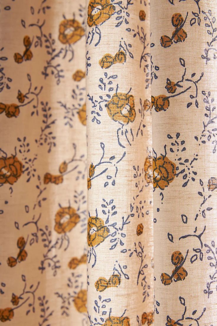 the curtain is decorated with yellow and blue flowers on cream background, closeup view