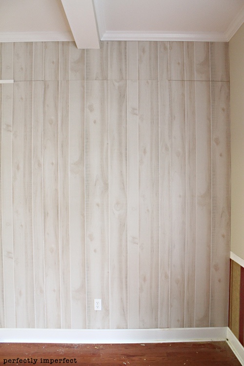 an empty room with wood flooring and striped wallpaper