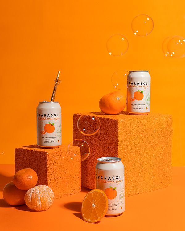 three cans of soda and oranges on top of blocks with bubbles coming from them