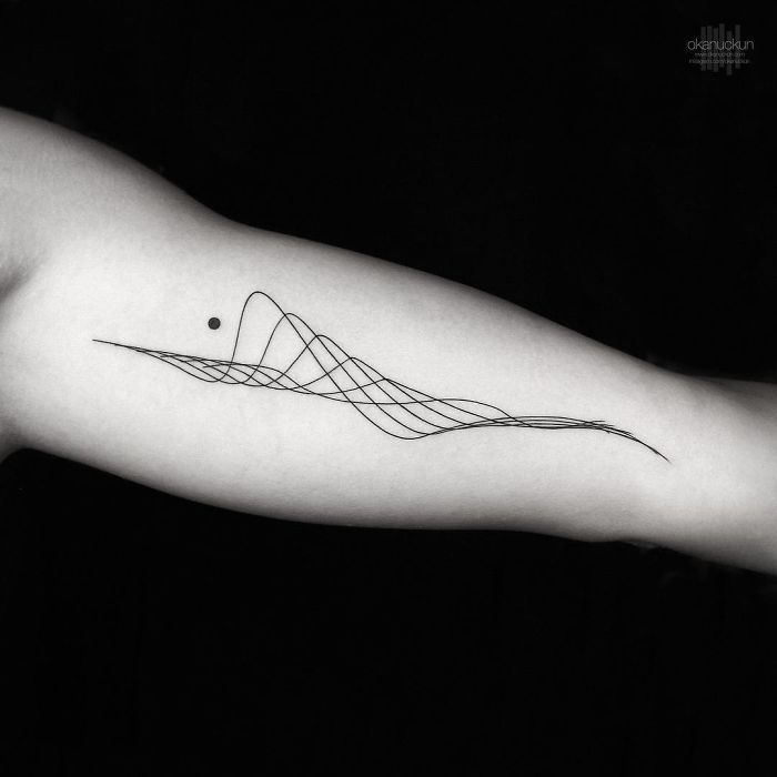 a black and white photo of a person's arm with a wave tattoo on it