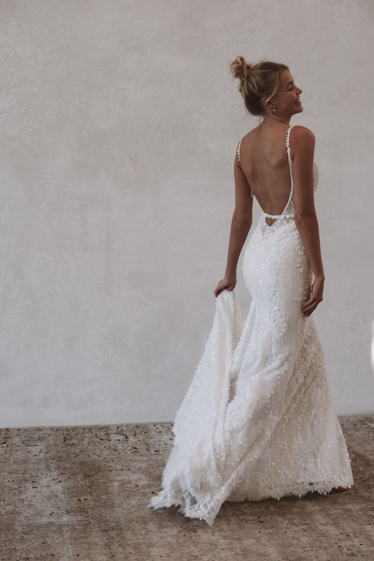 a woman in a white wedding dress standing on the ground with her back to the camera