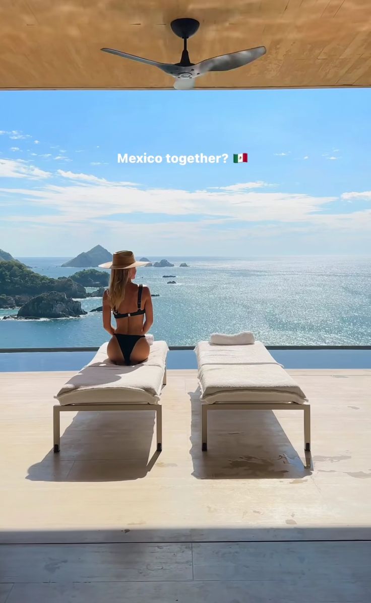 a woman sitting on top of a lounge chair next to the ocean