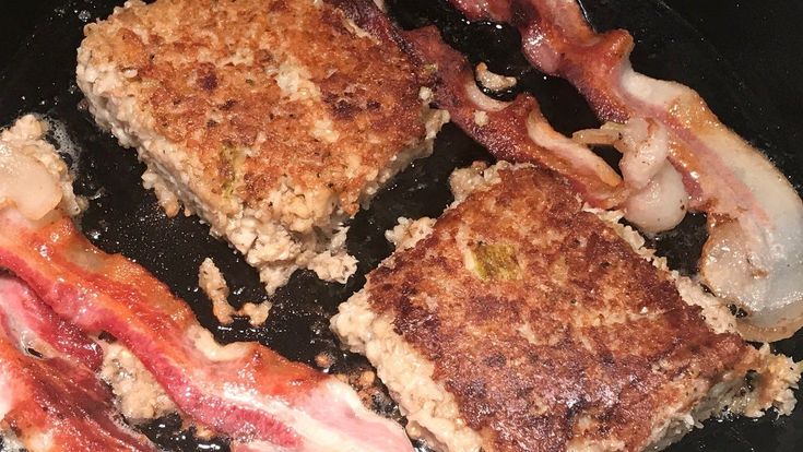 three pieces of meat cooking in a frying pan with onions and bacon on top