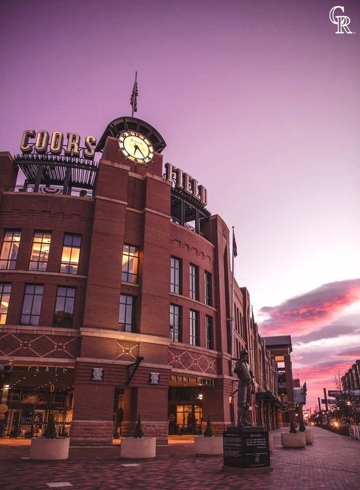 a large building with a clock on the top and an illuminated sign above it at dusk