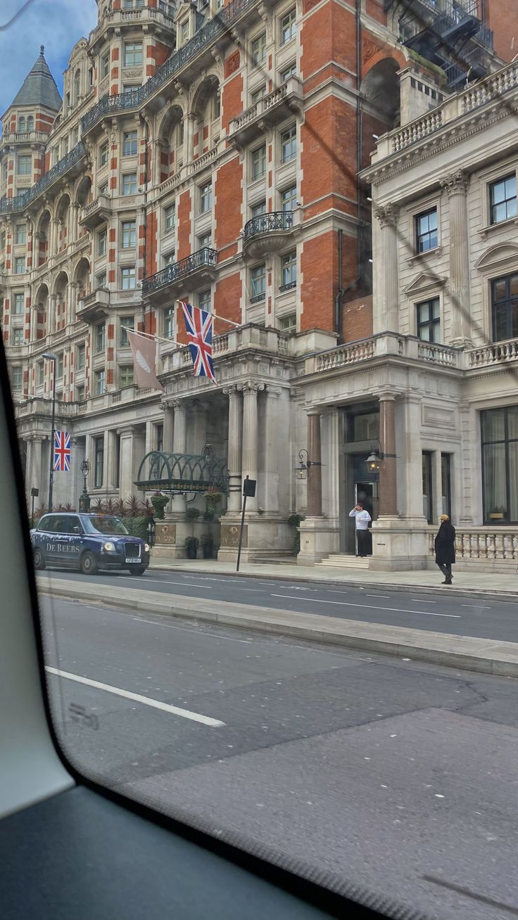 an old building with a british flag on it's roof and some cars parked in front