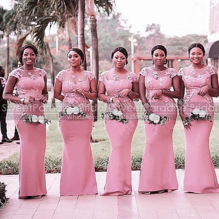 a group of women standing next to each other wearing pink dresses and holding bouquets