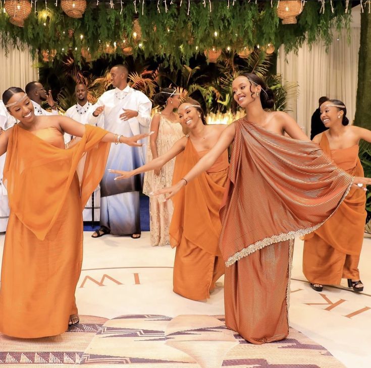 several women in orange dresses dancing on a dance floor