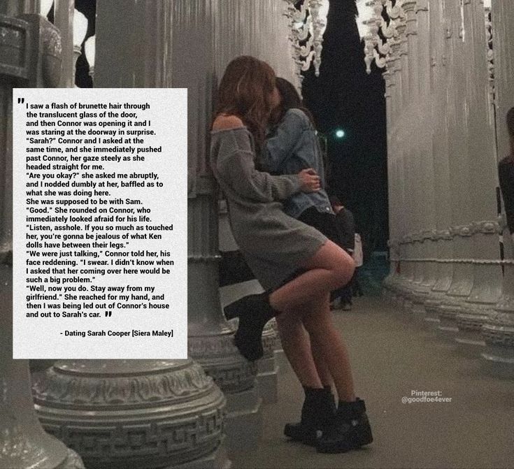 two women are hugging each other in front of chandeliers and columns with words written on them