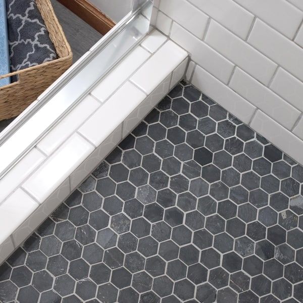 a bathroom with hexagonal tiles on the floor, and a basket in the corner