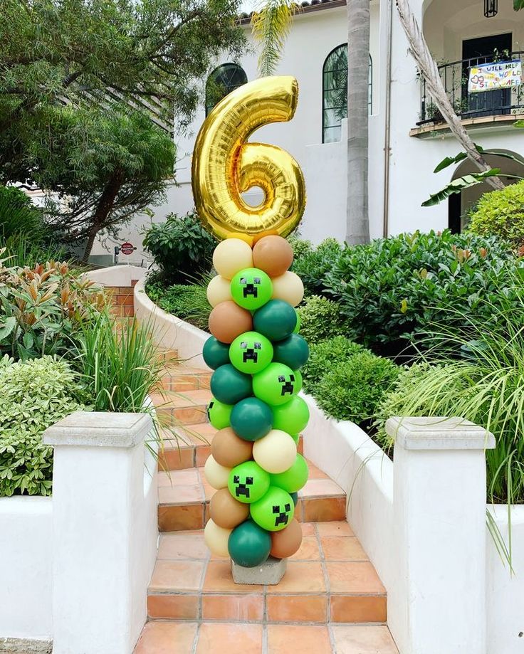 the number six balloon column is decorated with green, yellow and brown balloons in front of a house