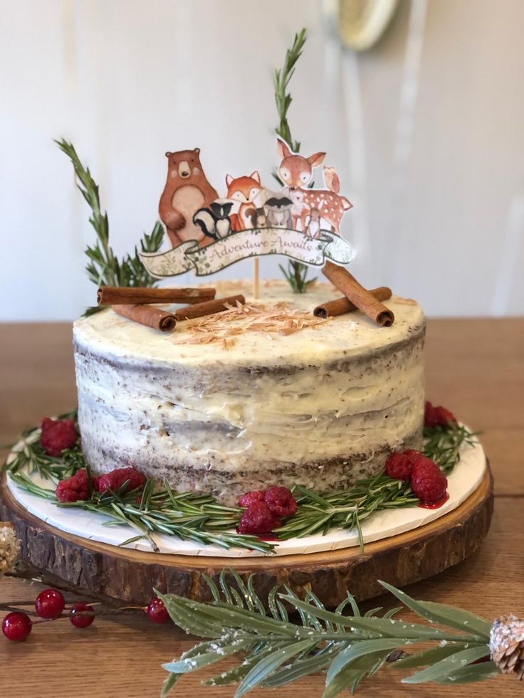 a cake with frosting and decorations sitting on top of a wooden table next to greenery