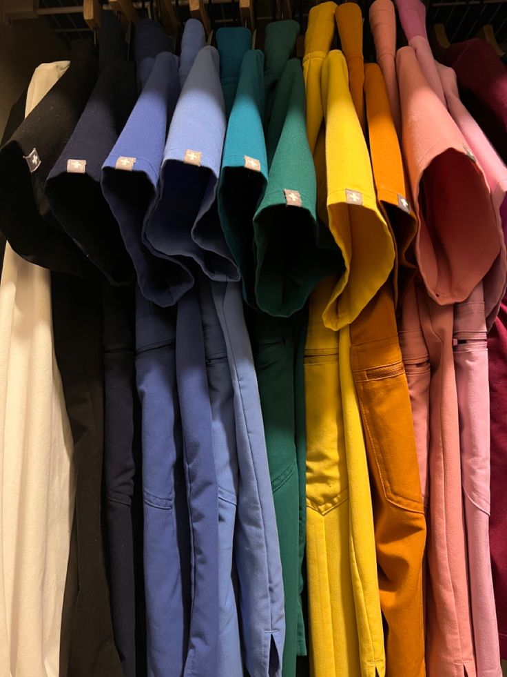 many different colored pants are hanging on a rack in the closet, and there is no image here to provide a caption for