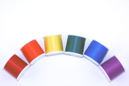 six spools of thread in different colors on a white background, with the top half showing