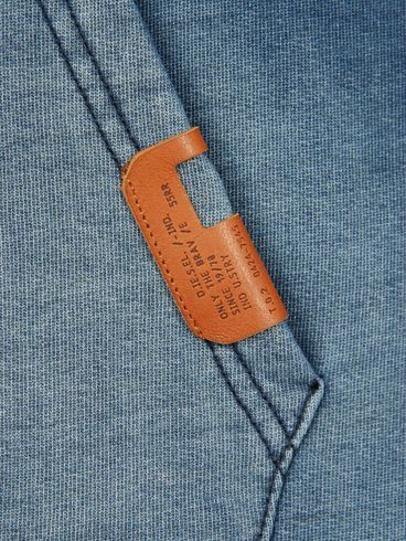 the back pocket of a blue shirt with a leather tag on it's chest