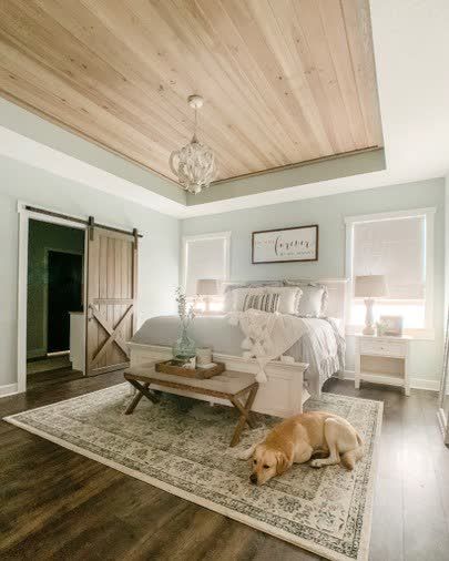 a dog laying on top of a rug next to a bed in a room with wooden ceilings