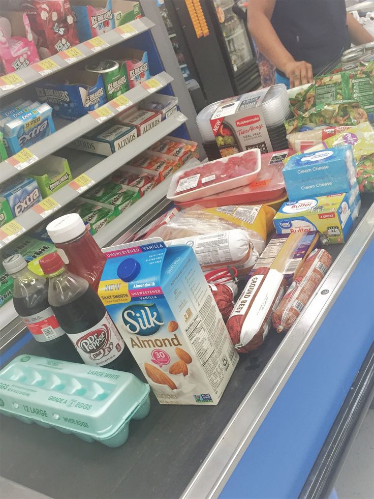 a person standing in front of a grocery store shelf filled with groceries and milks